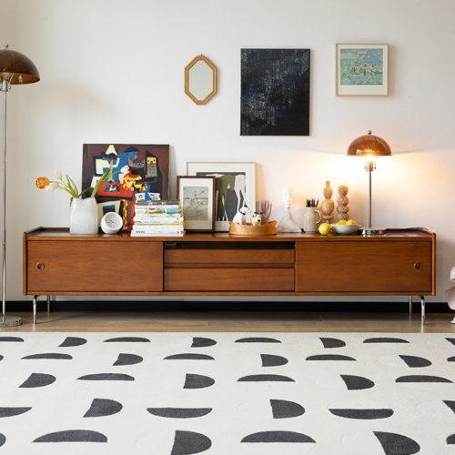 Wooden low console with art and lamps on top.