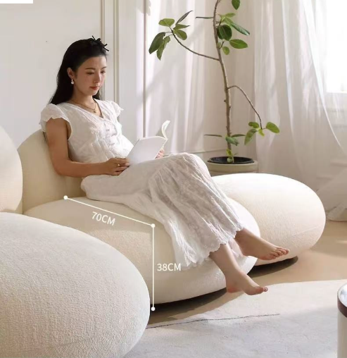 White plush bean bag chair with woman reading indoors.
