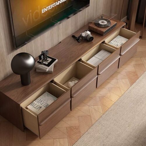 Modern wooden TV stand with open drawers and decor.