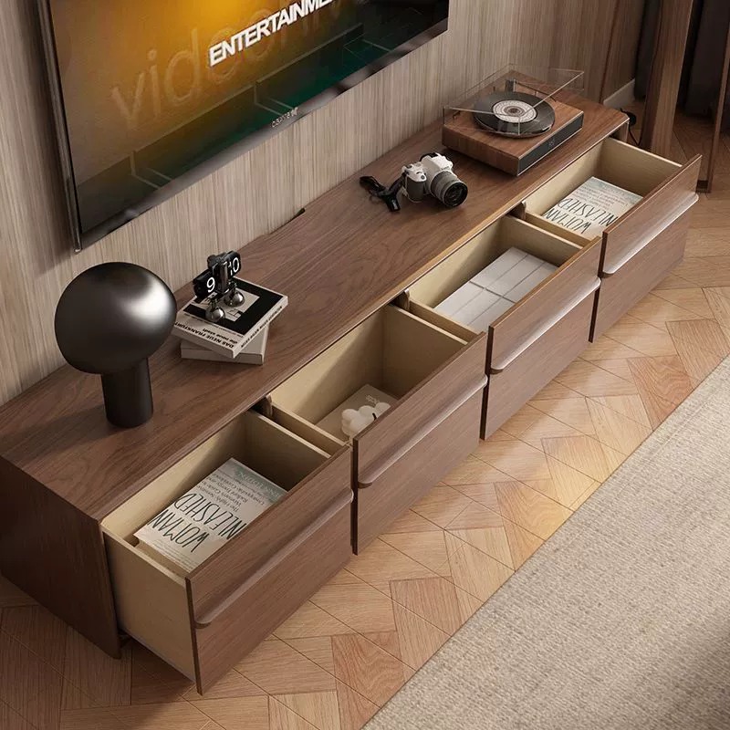 Modern wooden TV stand with open drawers and decor.