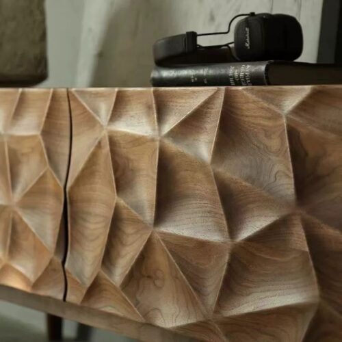 Geometric carved wooden sideboard with headphones and book.