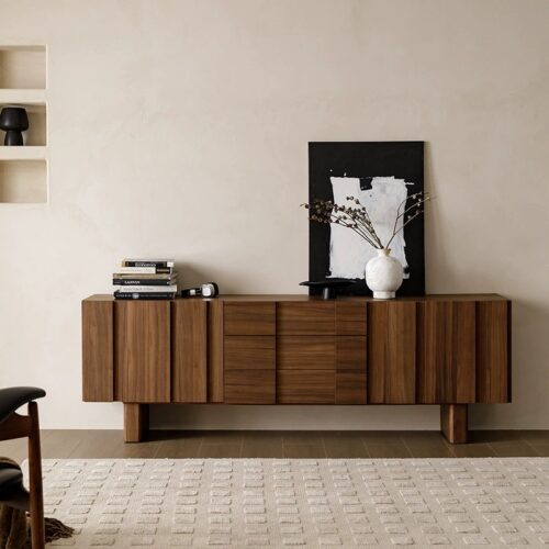 Modern wooden sideboard with drawers and decorative items.